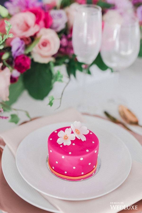 In questa foto una minicake di colore fucsia con pois di colore bianco e con fiori 