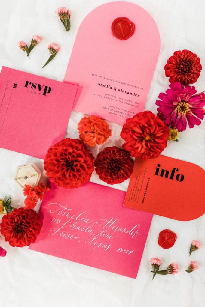 In questa foto una partecipazione matrimonio stile Barbie di colore rosa e rosso 
