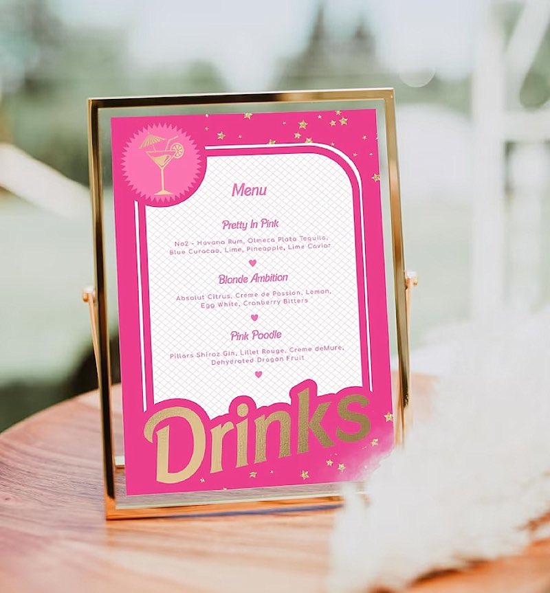 In questa foto un menù drinks di coloro fucsia con font di colore oro ispirato a Barbie