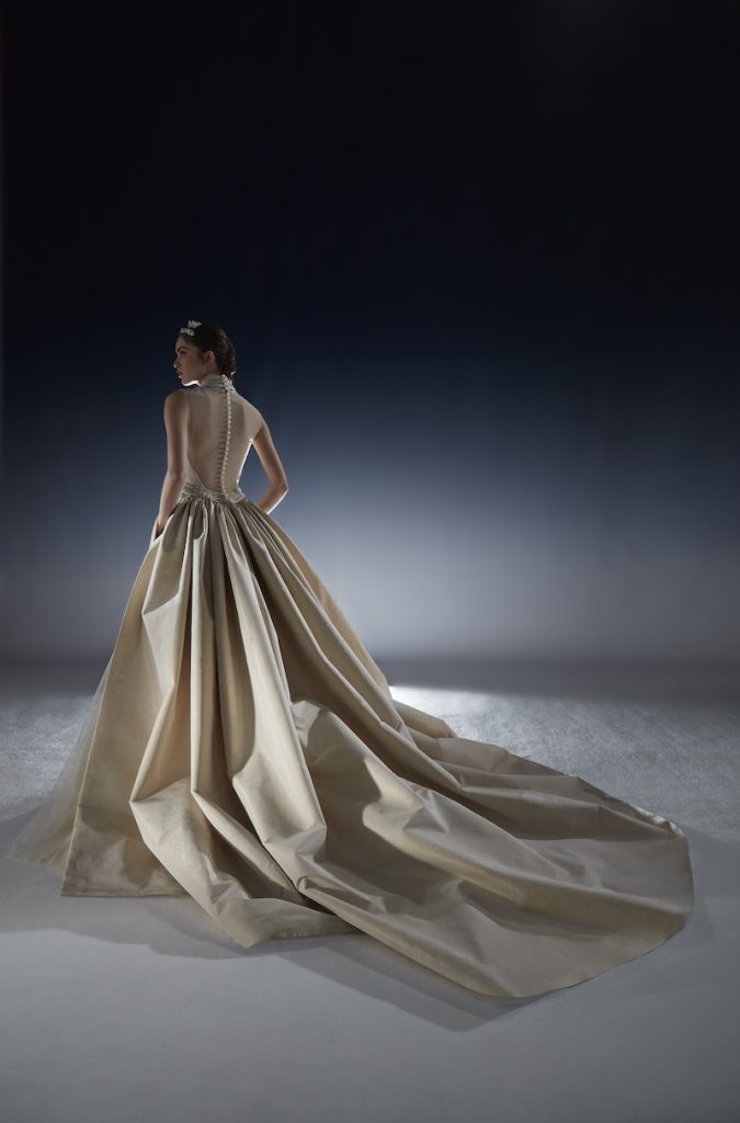 In questa foto una modella posa di spalle indossando un abito da sposa della collezione White Gold 2024 di Peter Langner in taffetà di colore avorio