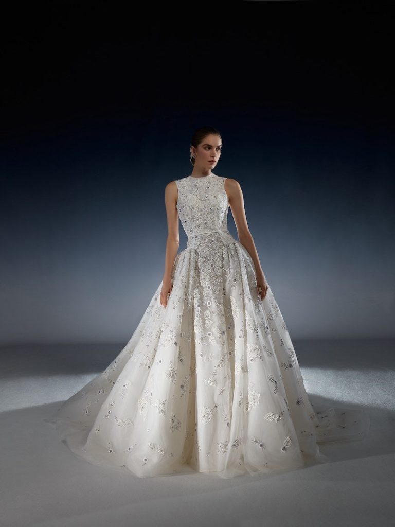 In questa foto una modella posa indossando un abito da sposa della collezione 2024 di Peter Langner con ricami 3D e scollatura Sabrina
