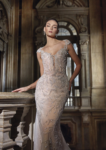 In questa foto una modella indossa un abito da sposa a sirena sparkling: fili di metallo e dettagli in lurex si intrecciano in un ricamo bucolico