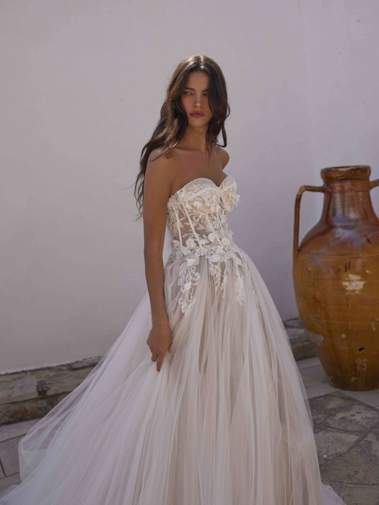 In questa immagine un abito da sposa con corpetto in pizzo floreale della collezione Capri 2024.