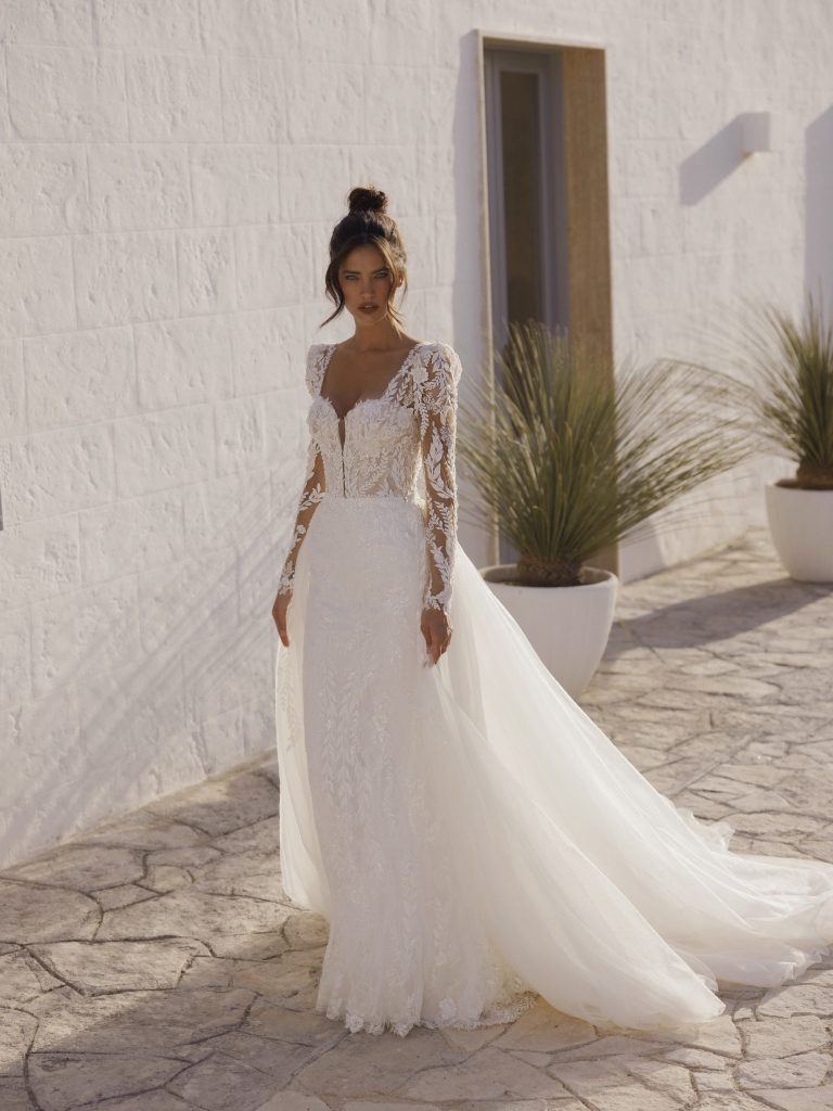 In questa immagine un abito da sposa in pizzo con maniche lunghe.