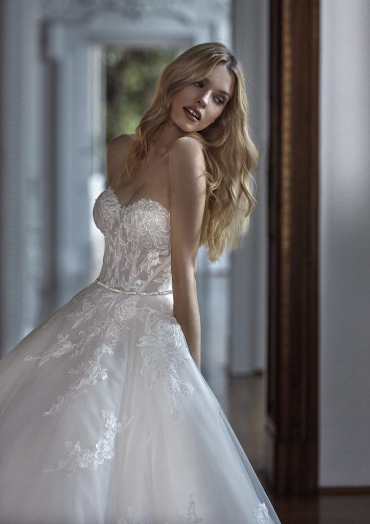 In questa foto una modella posa a mezzo busto indossando un abito da sposa principessa in tulle con bustier ricamato in pizzo rebrodè 