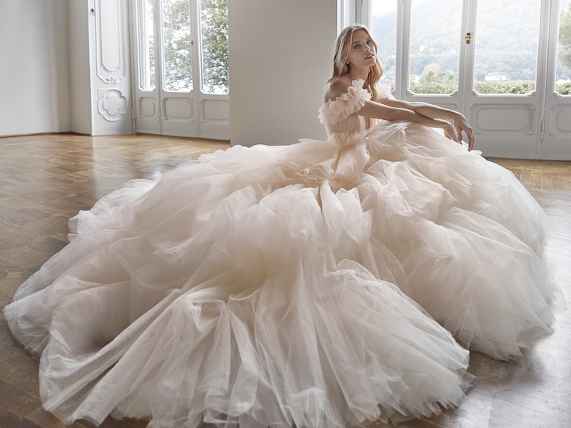 In questa foto una modella posa indossando un abito da sposa Nicole Milano 2024 modello principessa a balze in tulle