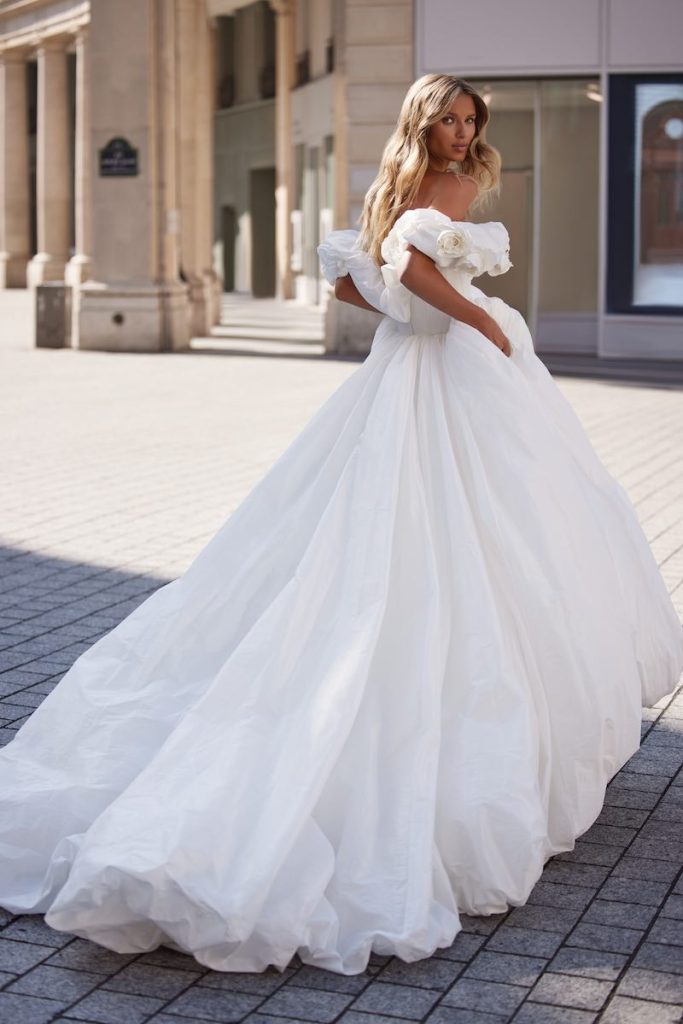 In questa foto una modella di spalle posa indossando uno degli abiti da sposa romantici 2024 Milla Nova in taffetà, ampio, con scollo a barca