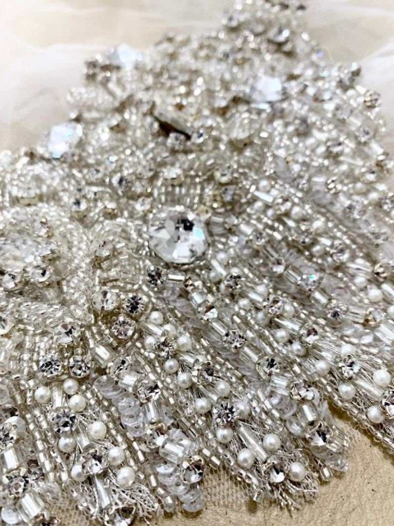 In questa foto il dettaglio di un tipo di pizzo con perline di diverse dimensioni per abito da sposa