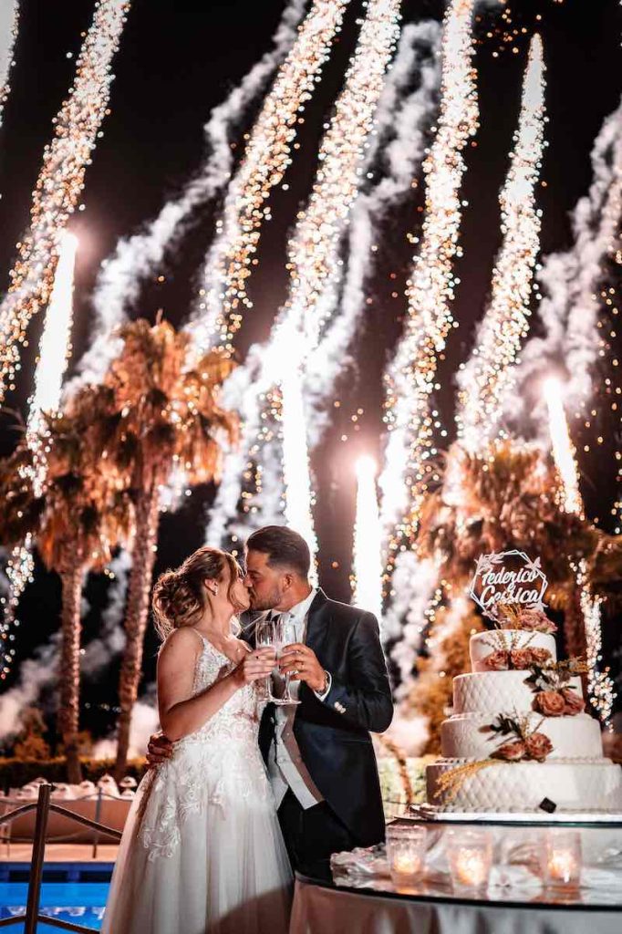 In questa foto di Virgilio Ferrara due sposi si baciano e brindano sullo sfondo di fuochi d'artificio