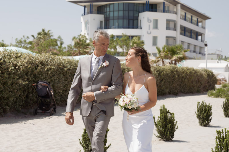 In questa foto una sposa cammina al braccio del padre sulla spiaggia del Blu Suite Resort 