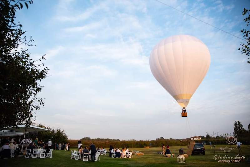 In questa foto uno dei matrimoni di Tenuta Corte Vittoria nel giardino visto da lontano e su cui vola una mongolfiera di colore bianco