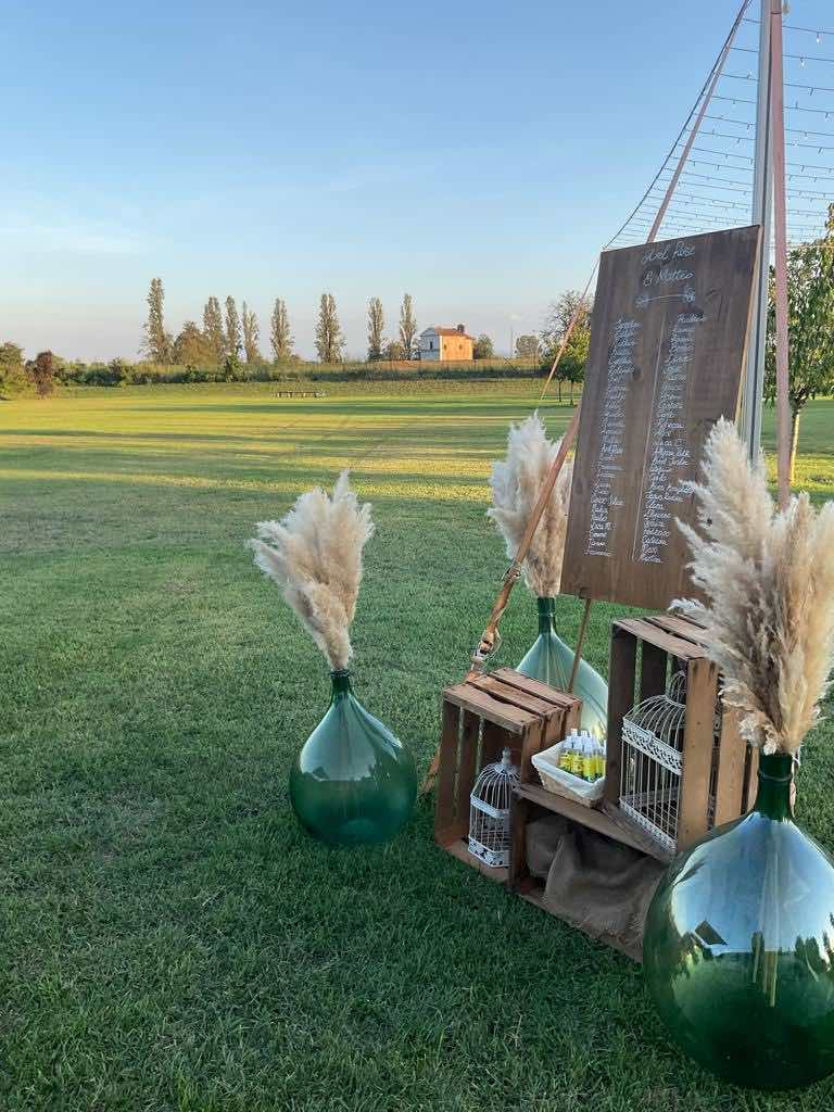 In questa foto un tableau in stile Country Chic decorato con pampas, cassette di  legno e damigiane di vetro sul giardino di Tenuta Corte Vittoria