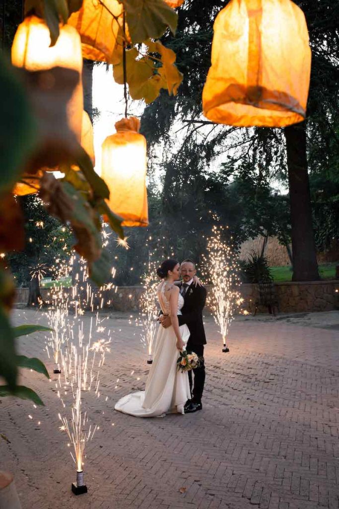 In questa foto gli sposi Alice e Michele si abbracciano sotto a lanterne di carta