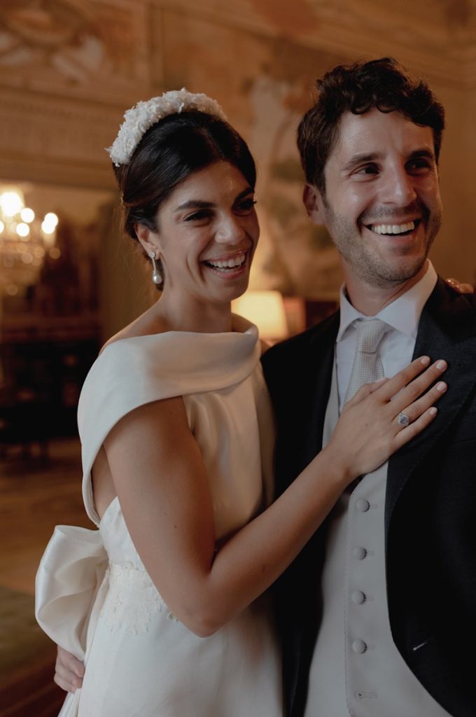 In questa foto gli sposi Elena e Nicola si abbracciano ridendo in uno dei saloni di Villa Tasca a Palermo