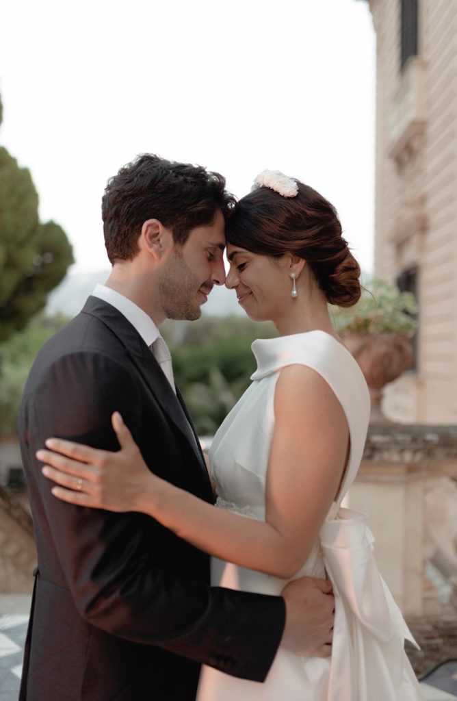 In questa foto gli sposi Elena e Nicola si abbracciano sorridendo sulla terrazza di Villa Tasca a Palermo