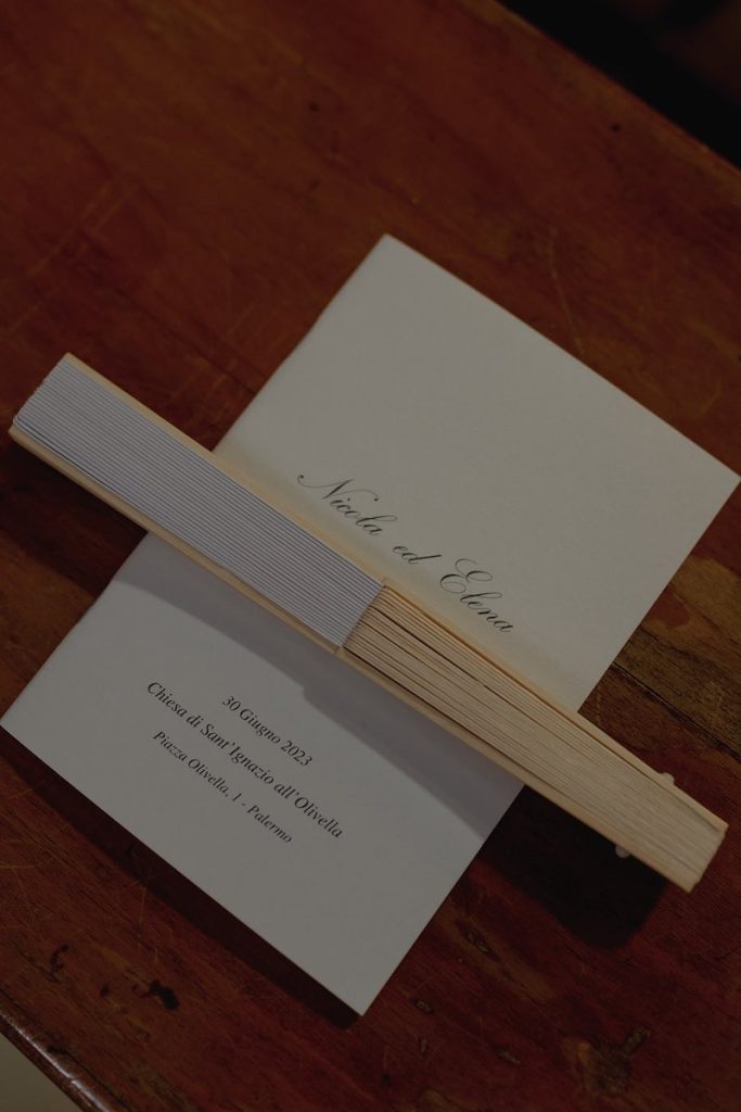 In questa foto il libretto messa del matrimonio di Elena e Nicola poggiato su uno dei banchi della chiesa insieme ad un ventaglio