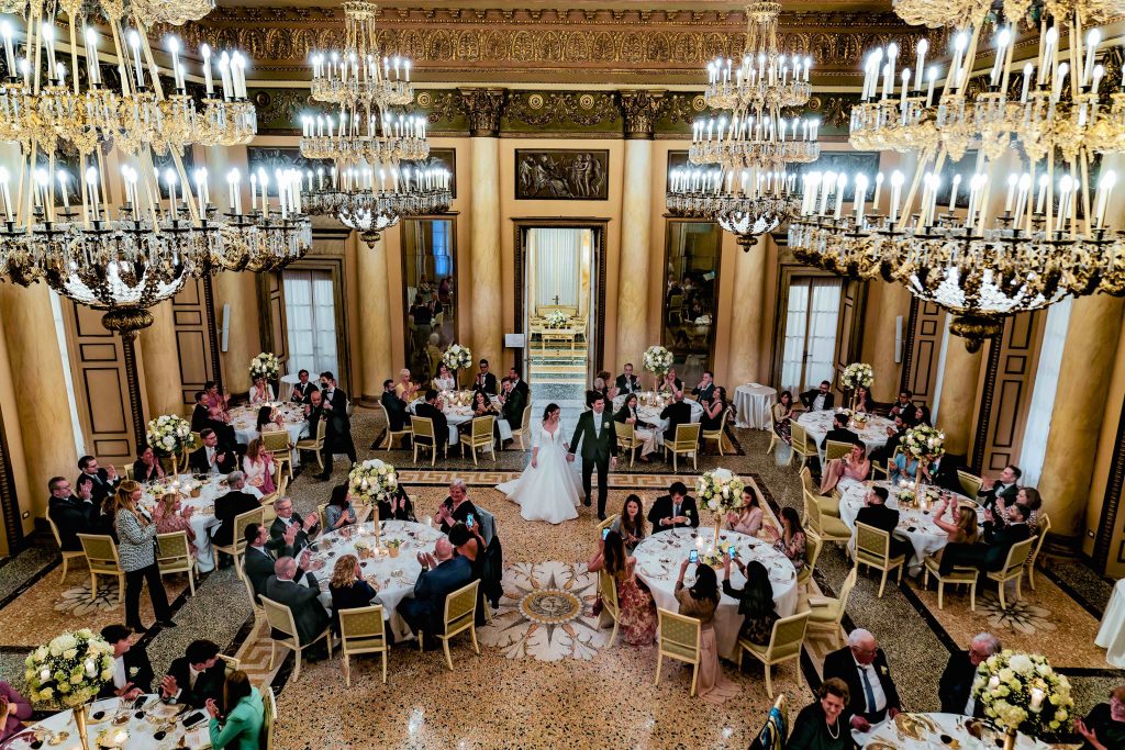 In questa immagine gli sposi entrano in sala con tutti gli invitati già seduti. 