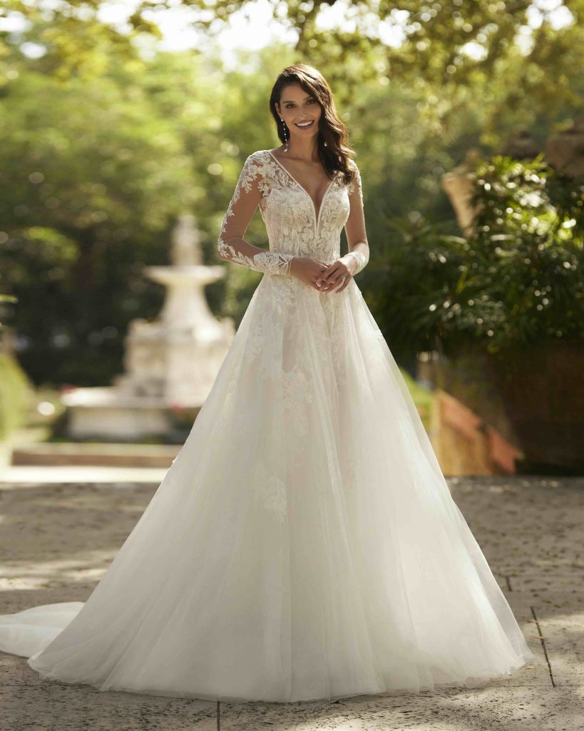 In questa immagine un vestito da sposa con maniche in pizzo e gonna in tulle di Aire Barcelona. 