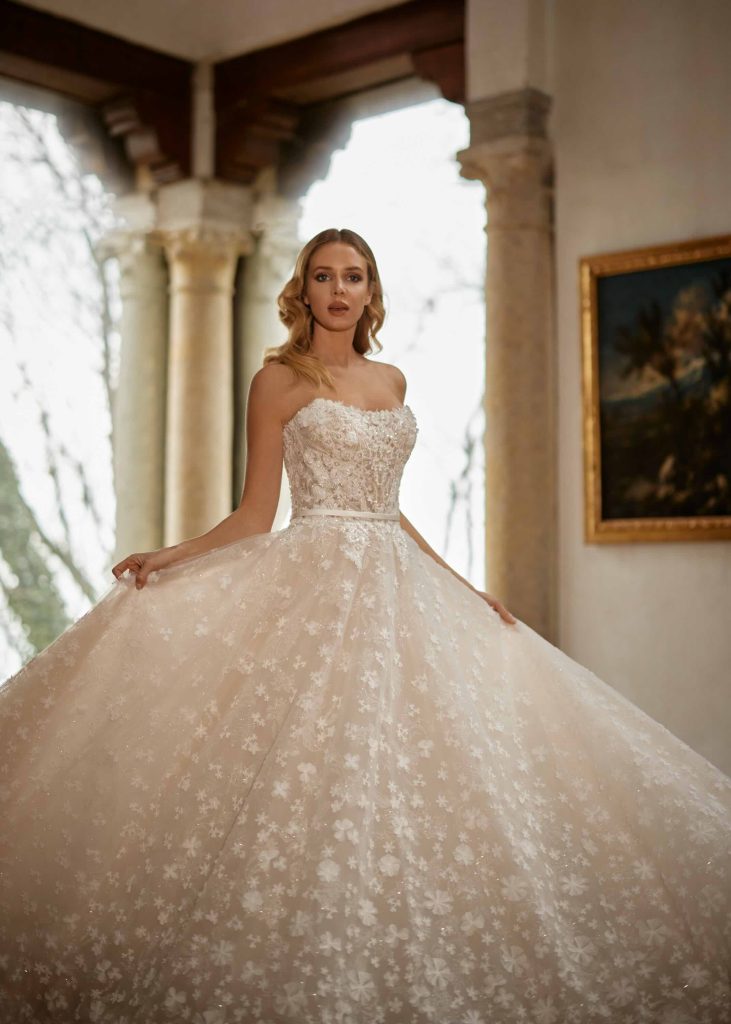 In questa immagine un abito da sposa da principessa 2024 interamente ricoperto da dettagli floreali in pizzo di Randy Fenoli