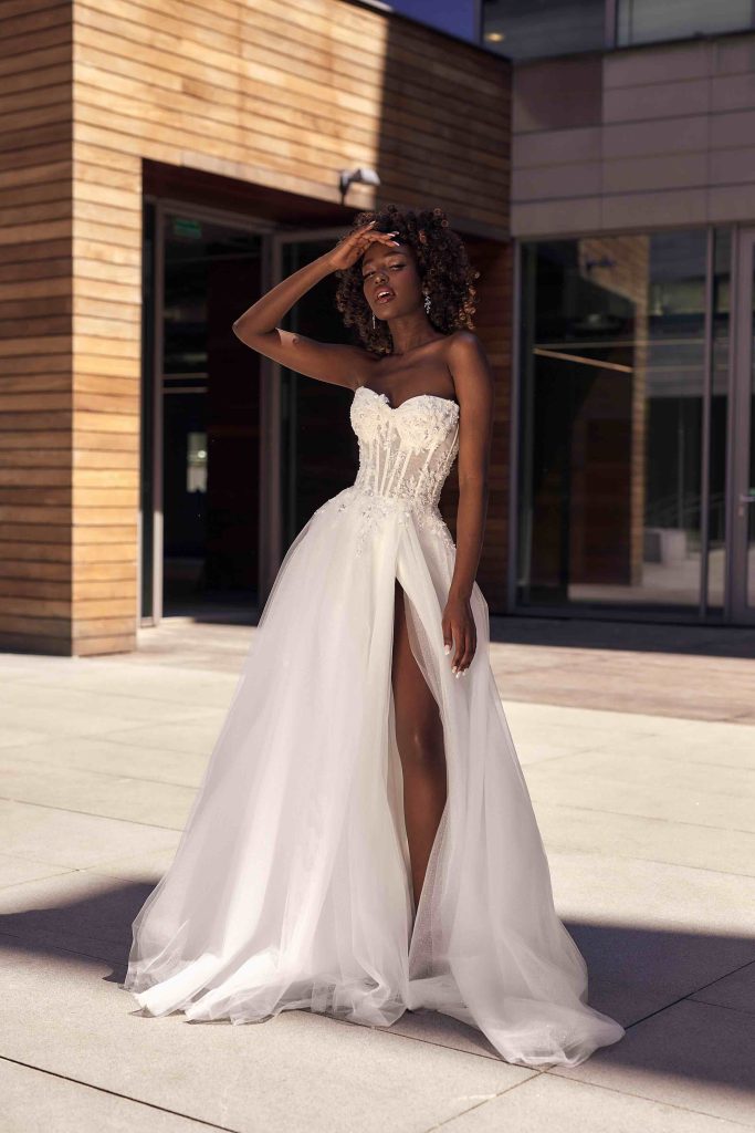 In questa immagine un modello di Annais Bridal con spacco profondo e corpetto in pizzo che fa parte degli abiti da sposa seducenti 2024.