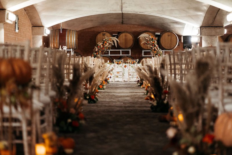 In questa foto l'allestimento di un matrimonio simbolico in barricaia firmato da Erica Canova e realizzato nei toni dell'arancione con zucche, pampas e candele