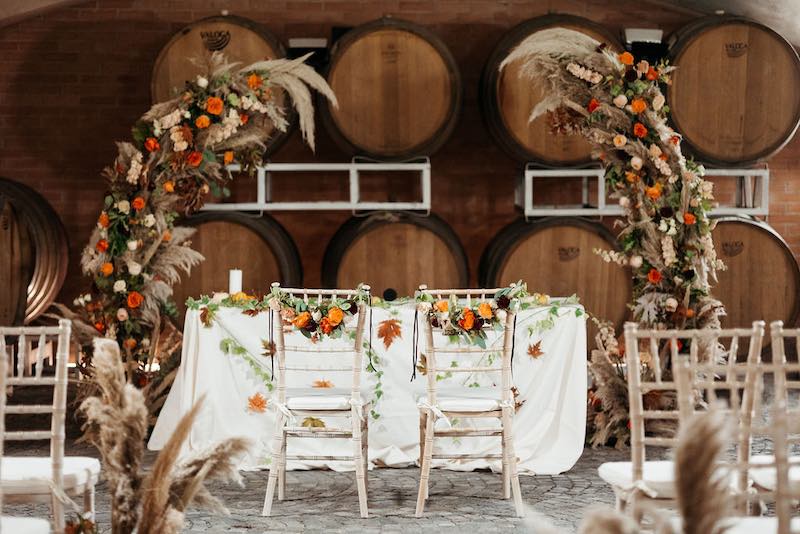 In questa foto il dettaglio dell'allestimento di un matrimonio simbolico in barricaia firmato da Erica Canova e realizzato nei toni dell'arancione con zucche, pampas e candele
