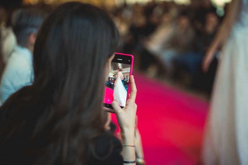 In questa foto una ragazza di spalle mentre fotografa una modella che sfila a Bergamo Sposi