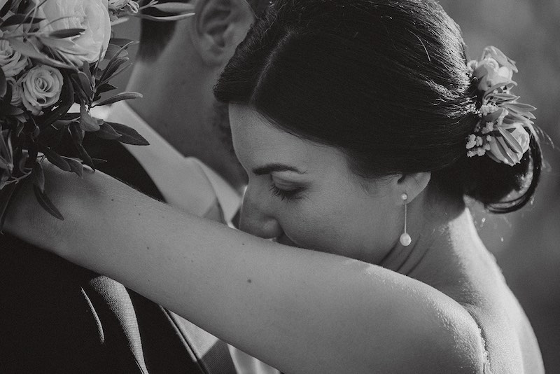 In questa foto in bianco e nero di Alessandro Tondo due sposi si abbracciano. La sposa posa la tesa sulla spalla dello sposo