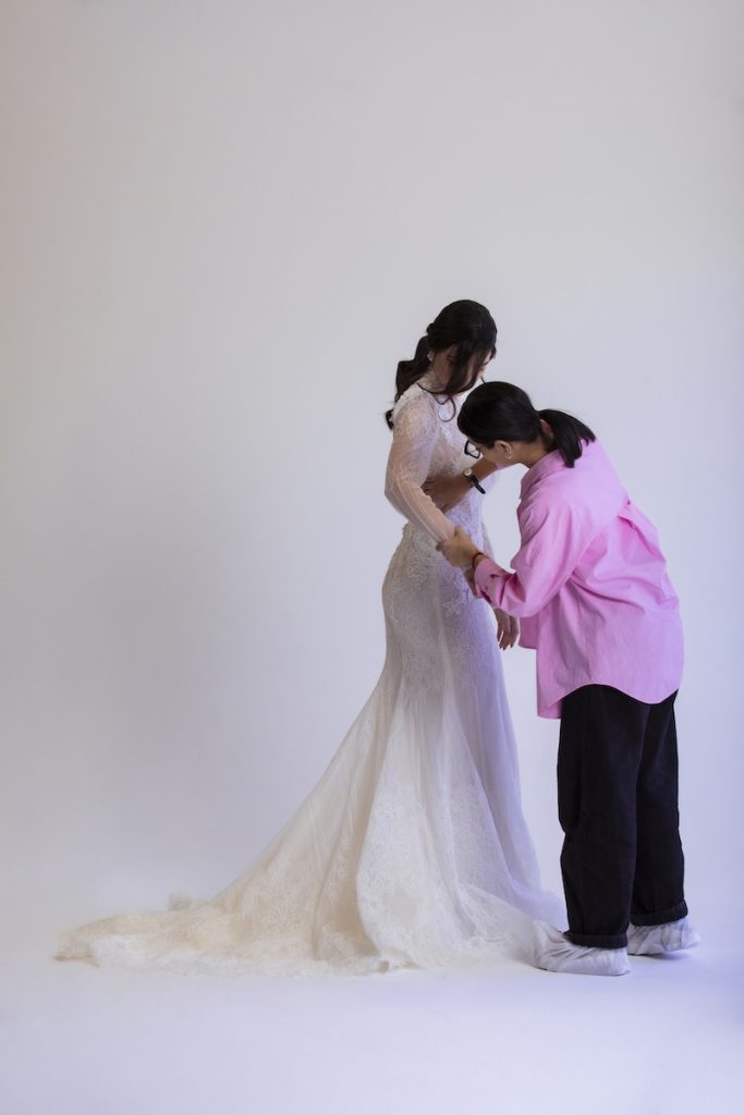In questa foto la Bridal Stylist Giulia Solli di spalle sistema l'abito da sposa su una modella durante uno shooting 