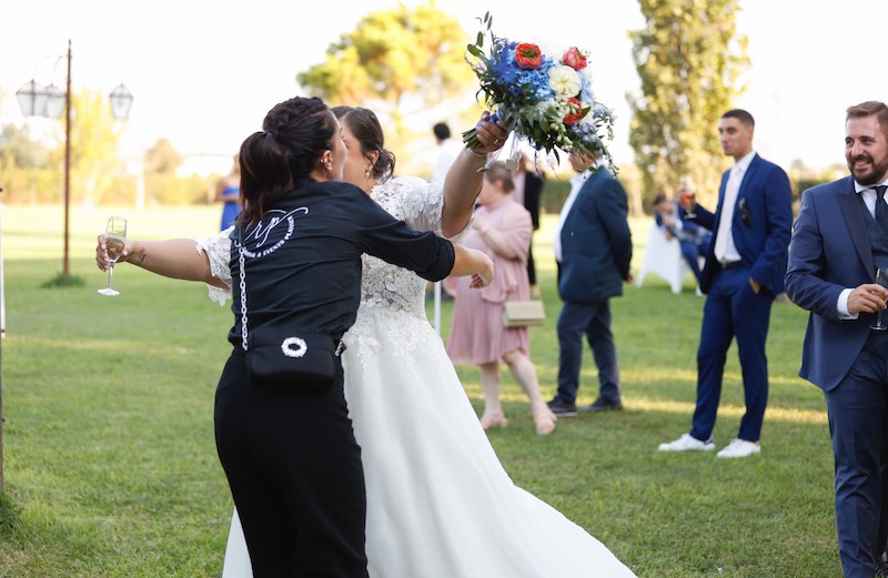 In questa foto la Wedding Planner Romina Pecorati di spalle abbraccia una sposa su un prato