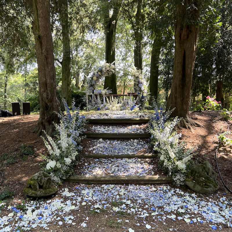 In questa foto una cerimonia civile allestita in un bosco con petali e fiori di colore bianco e lilla dalla Wedding Planner Romina Pecorari