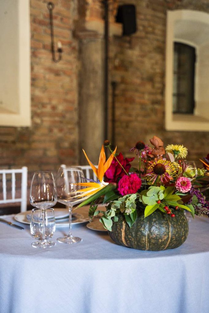 In questa foto il centrotavola delle nozze di Silvia e Alessandro progettato da OttoQuattro Eventi con una zucca ricolma di sterlizia, rosa, bacche garofani, eucalipto