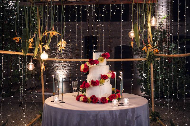 In questa foto la torta nuziale di Silvia e Alessandro progettata da OttoQuattro Eventi a quattro piani con elica di fiori di colore rosso, giallo e arancione
