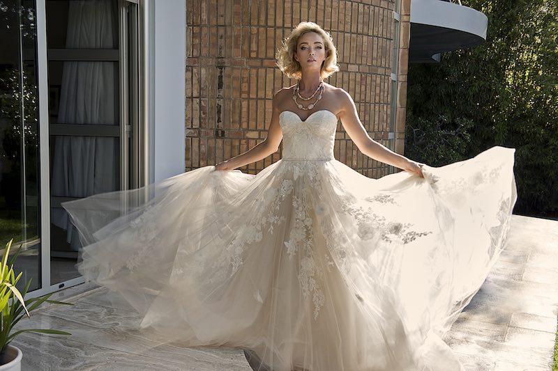 In questa foto una modella posa indossando un abito da sposa in tulle con ramage floreale di Jillian, tra gli stilisti dell'atelier Le Fate Milano