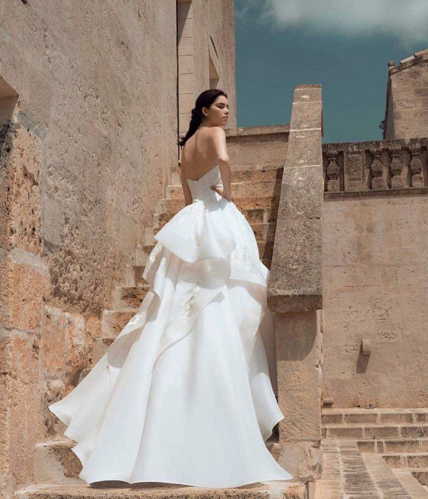 In questa foto una modella posa di spalle sulle scale di un'antica villa indossando un abito ampio di Rosanna Perrone