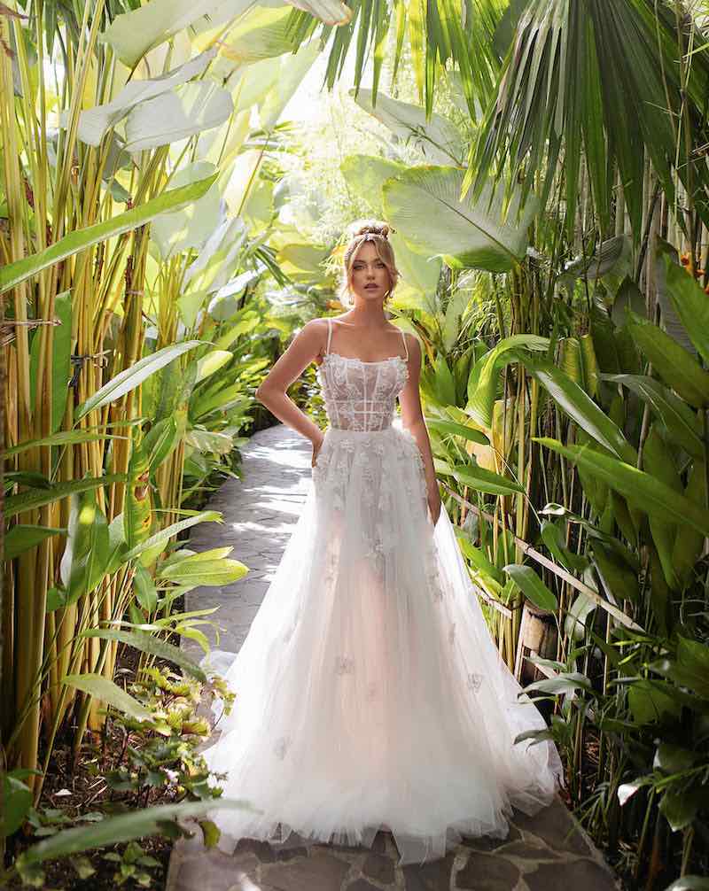 In questa foto una modella posa indossando un abito da sposa Agnieszka Swiatly 2024
con gonna ad A in tulle, scollo quadrato, bustier e microfiori 3D