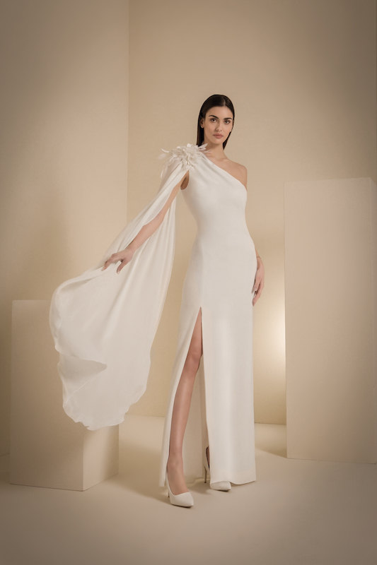 In questa foto un abito da sposa monospalla, con applicazione floreale sulla spalla da cui si allunga un'ala di tessuto, della collezione sposa 2024 di D'Errico 