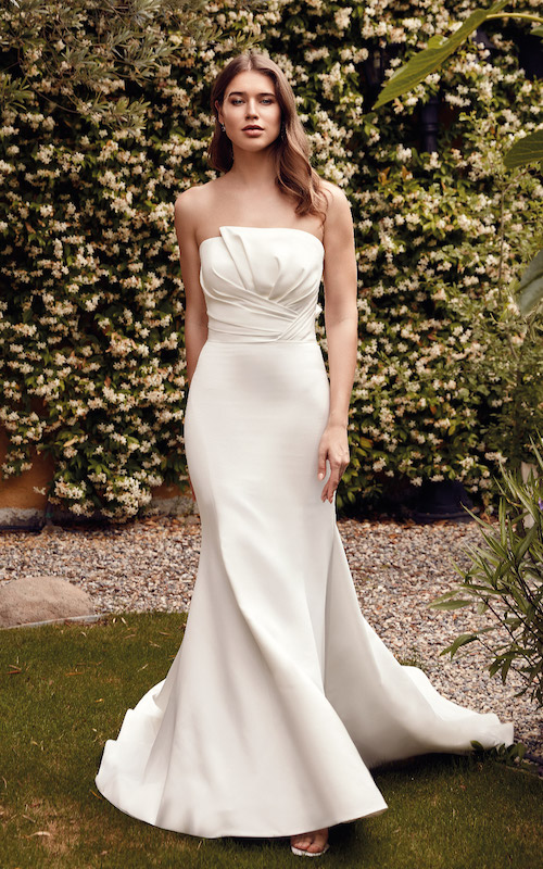In questa foto una modella indossa un abito da sposa a sirena total white, con elegante drappeggio sul copertto. Il vestito è di Eddy K per il 2024