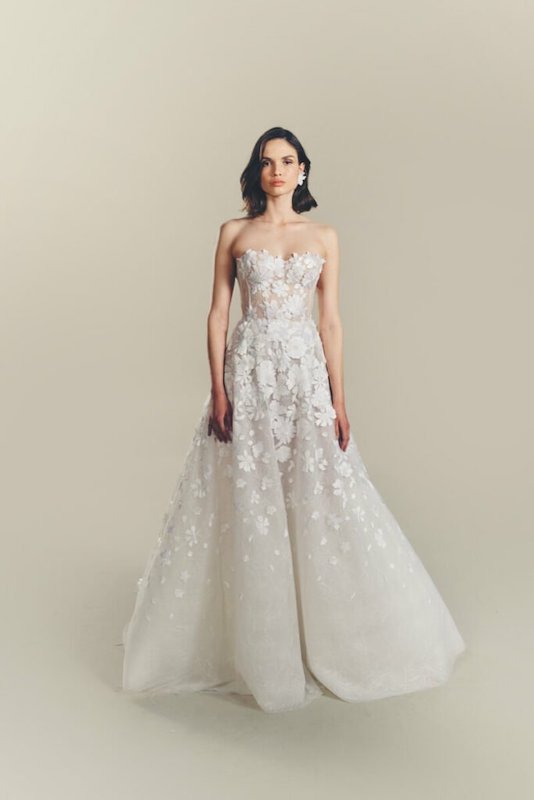 In questa foto una modella indossa un abito da sposa scivolato, con applicazioni floreali e scollo a cuore, di Mira Zwillinger