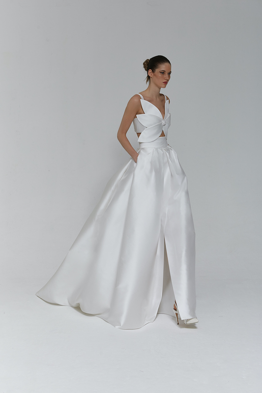 In questa foto una modella indossa un abito da sposa Tosca Spose: fa parte dei 100 vestiti da sposa 2024 più belli. La sua particolarità sta nel corpetto, che ha la forma di un fiore con grandi petali