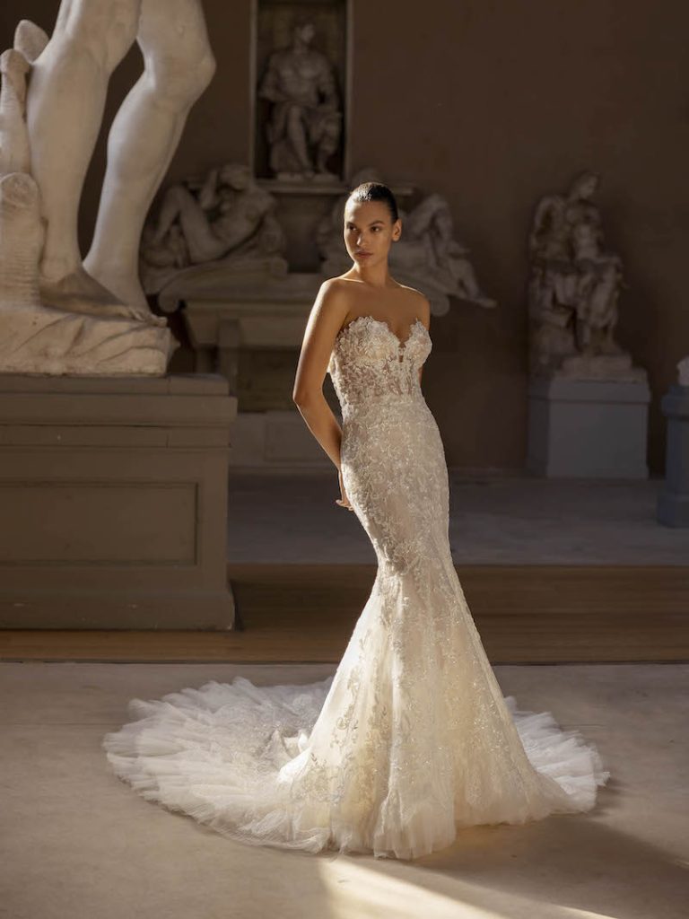 In questa foto una modella indossa un abito da sposa a sirena 2024 Modeca della collezione Zephyr Couture by Modeca in tulle con ricami di strass e scollo a cuore