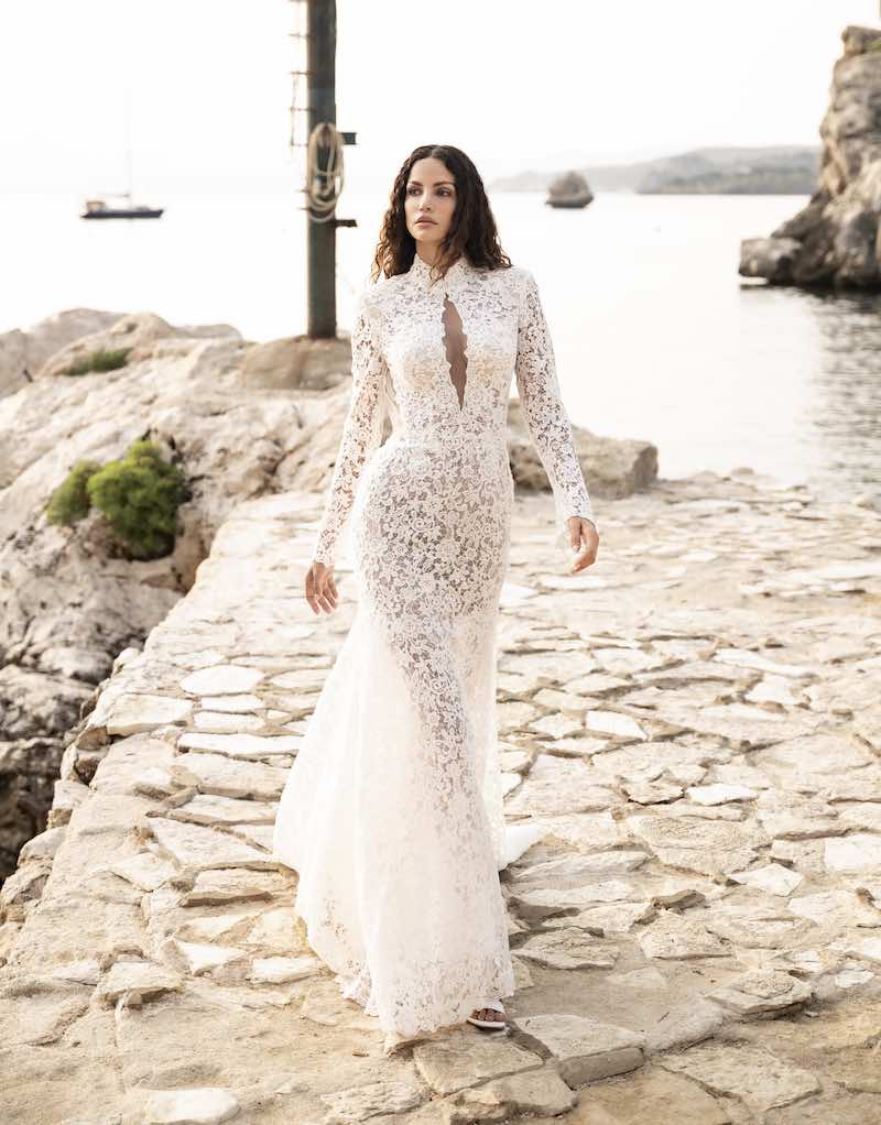 In questa foto una modella indossa un abito da sposa a sirena in pizzo macramè di Alessandro Angelozzi con scollatura ad oblò e maniche lunghe