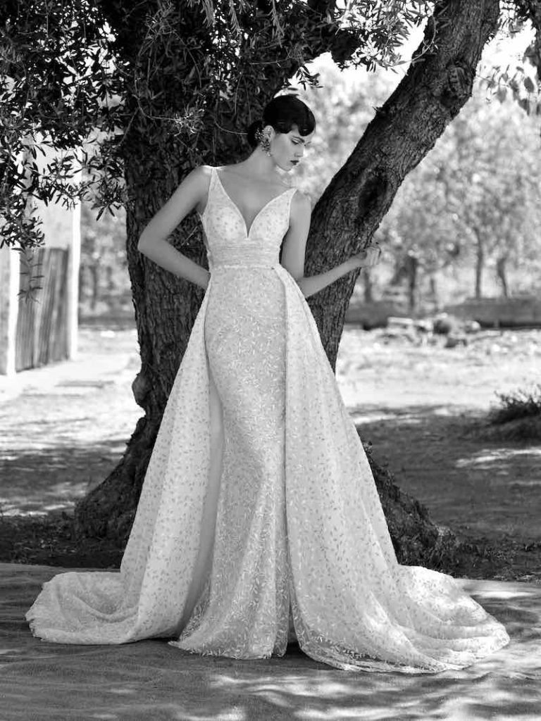 In questa foto in bianco e nero una modella indossa uno dei modelli di abiti da sposa a sirena 2024 Higar Novias con sopragonna staccabile