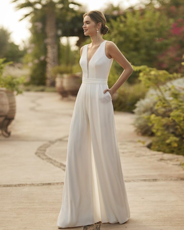In questa una modella indossa uno degli abiti da sposa con pantaloni palazzo 2024 di Alma Novia