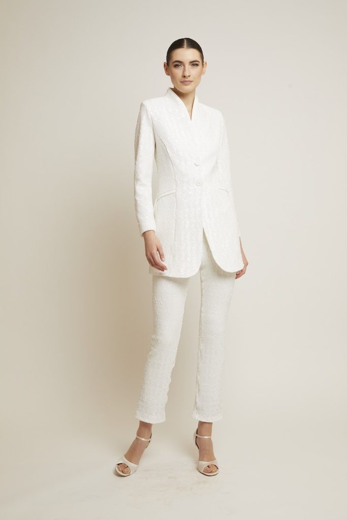 In questa foto una modella indossa un completo da sposa 2024 con pantaloni e blazer lungo di Chiara Boni