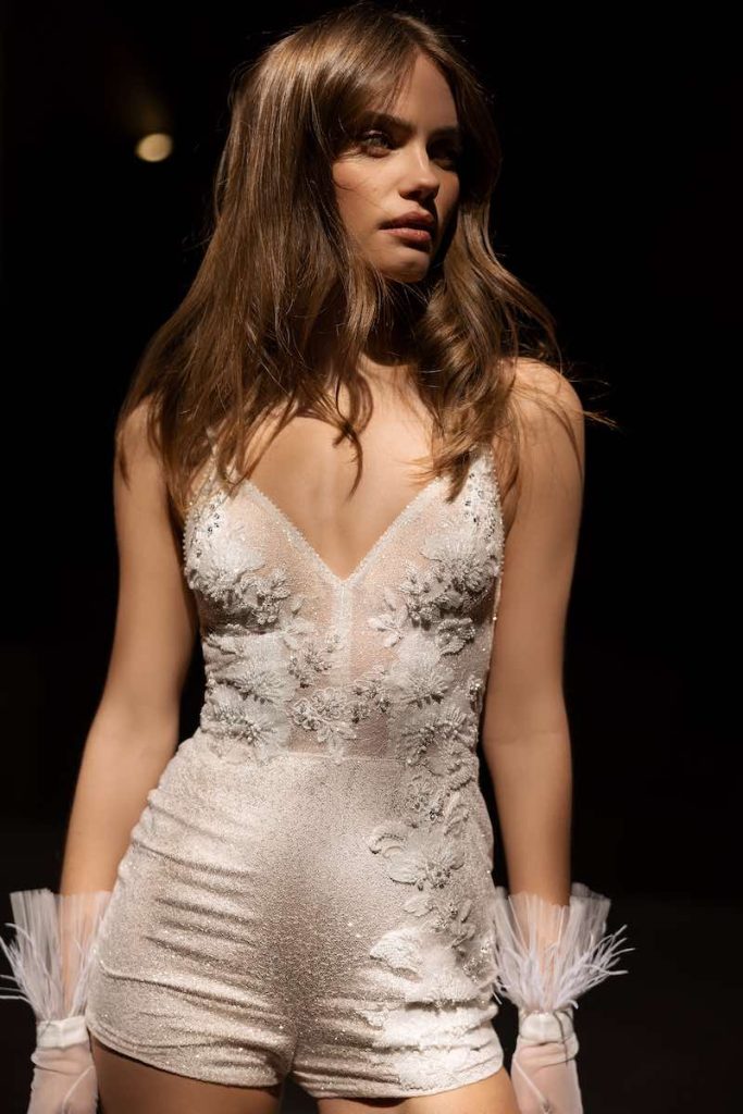In questa foto una modella indossa una tuta da sposa con cristalli e fiori 3D con shorts di Eva Lendel