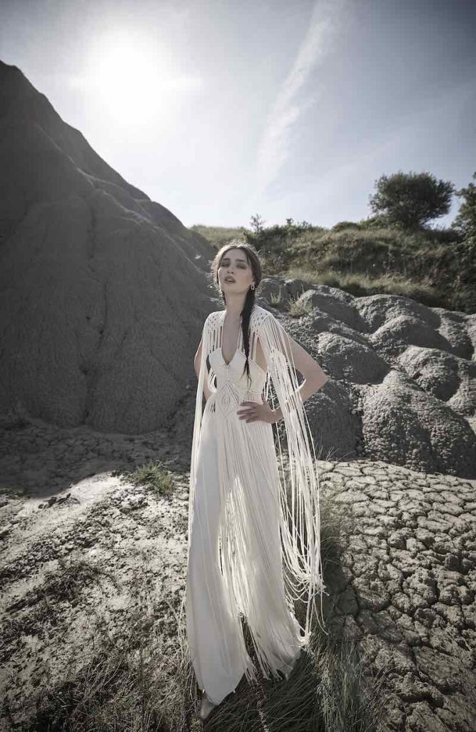 In questa foto una modella indossa un a tuta da sposa con lunghe frange che scendono dalle spalle di Luisa Sposa