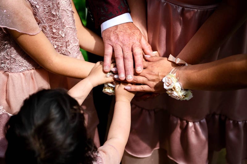 In questa foto le mani du una famiglia le une sulle altre durante un rito simbolico personalizzato con la celebrante Gabriella Maran