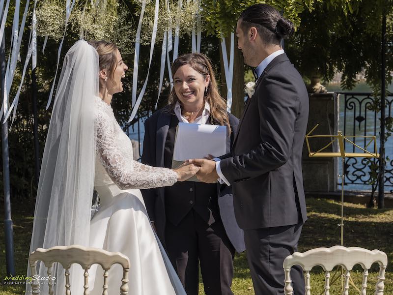 In questa foto la celebrante Gabriella Maran durante la celebrazione delle nozze di due sposi che si tengono per mano. La sposa ride