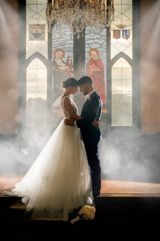 In questa foto in controluce di Claudio Fasci due sposi abbracciati in una chiesa e circondati da fumo